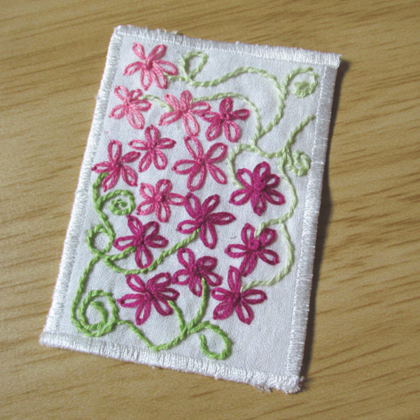 white linen ACEO with embroidered pink flowers and green vines