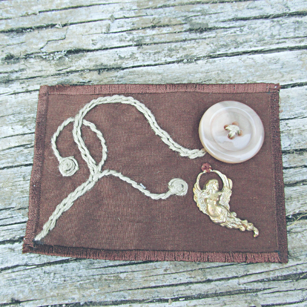 brown silk ACEO with a vintage button flower, embroidered vines, and a vintage brass fairy charm