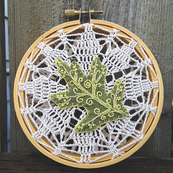Embroidery hoop with vintage lace and an embroidered green oak leaf