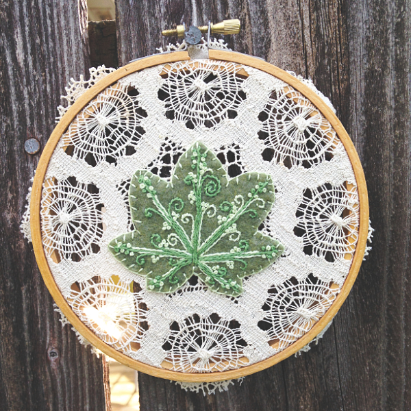 embroidery hoop with a green embroidered leaf and vintage lace