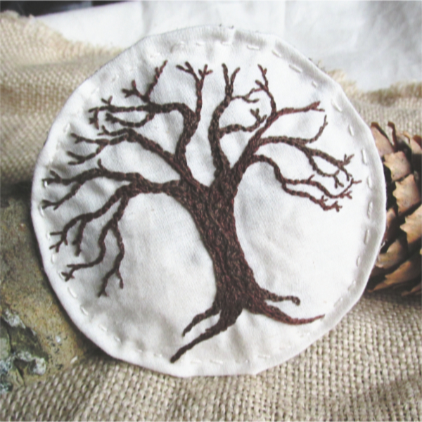a bare tree embroidered on a beige muslin background