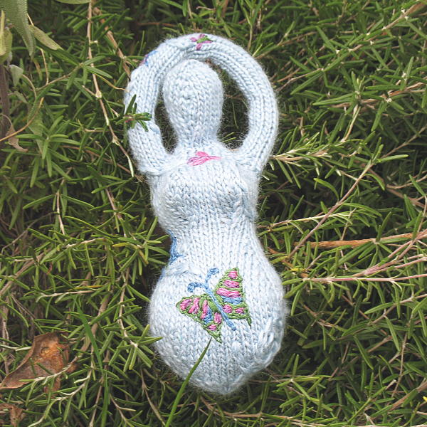 a pale blue knitted goddess with an embroidered butterfly on her belly