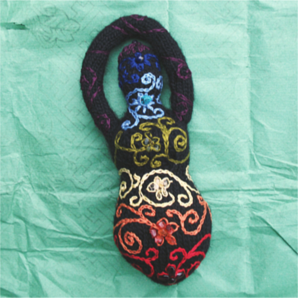 a black knitted goddess embellished with spirals in all the shades of the rainbow