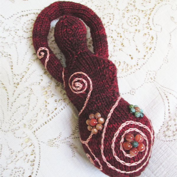 wine red knitted goddess with embroidered spirals and beaded flowers