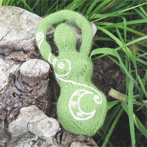a green knitted goddess with a white embroidered moon and spirals