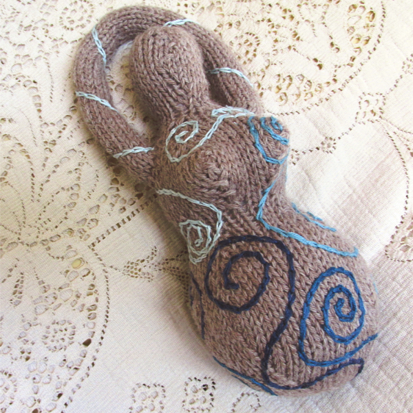 tan knitted goddess with embroidered spirals in shades of blue
