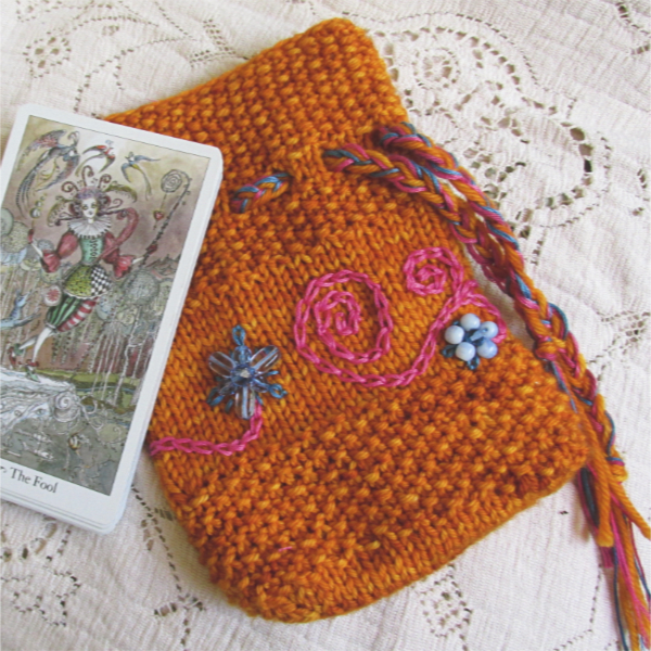 orange knitted tarot pouch with pink embroidered spirals and blue beaded flowers