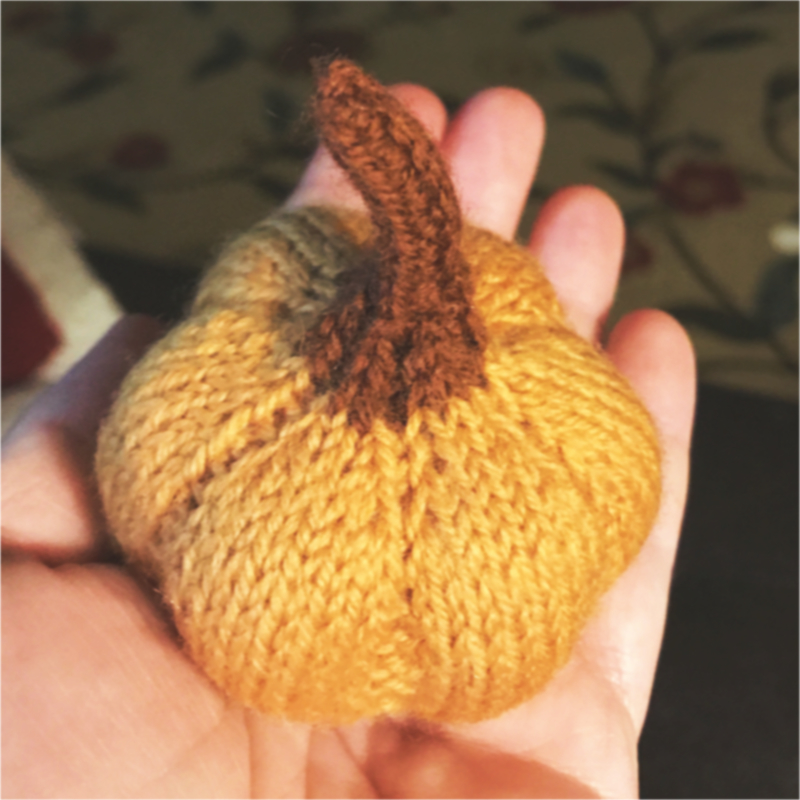 palm sized knitted pumpkin with pale orange body and brown stem