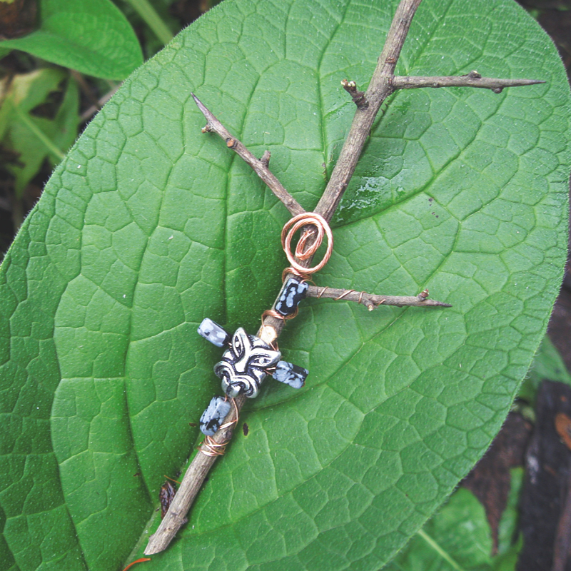 thorny branch adorned with copper wire spirals, snowflake obsidian beads, and a mask bead
