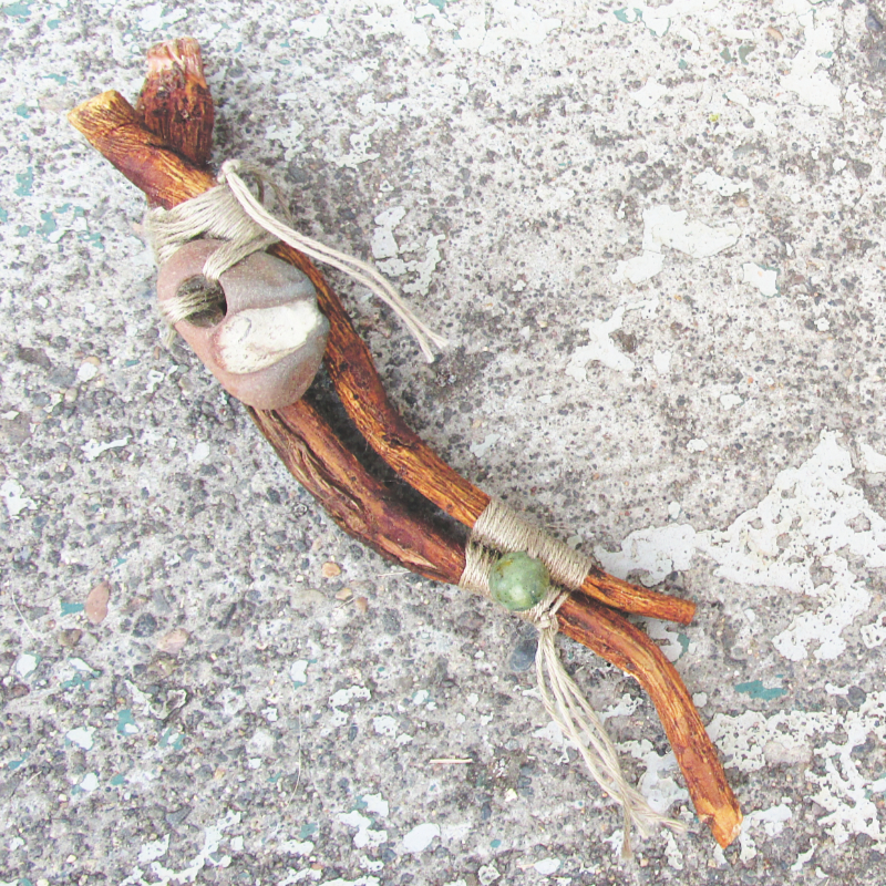 dandelion roots woven together with twine, adorned with a hagstone and a turquoise bead
