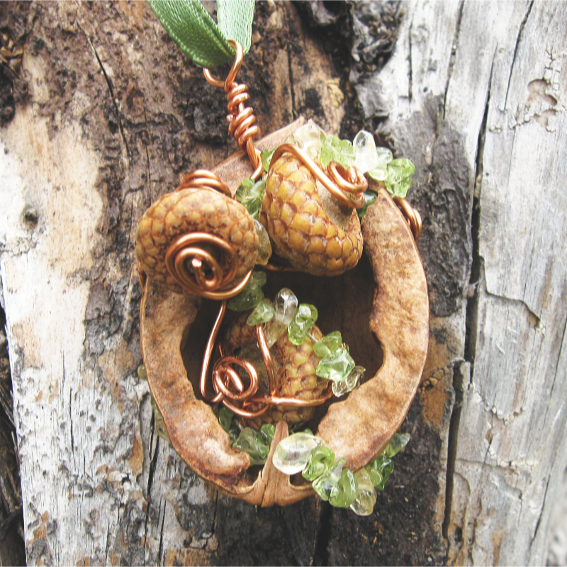 half a walnut shell filled with tiny acorns, citrine, and peridot beads, with copper wire spirals.