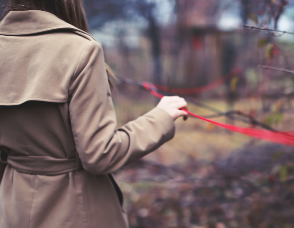 a woman holds a red string that's connected to many trees