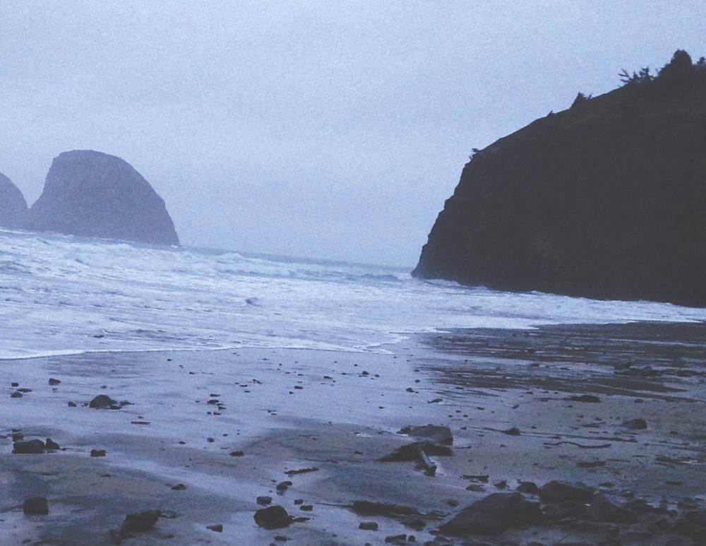 large rock formations in the Pacific ocean just off a stormy shoreline