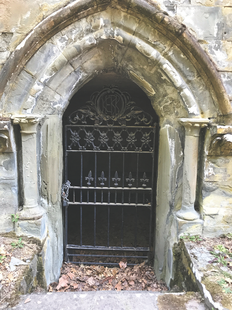 An ornate iron gate in an arched stone entry