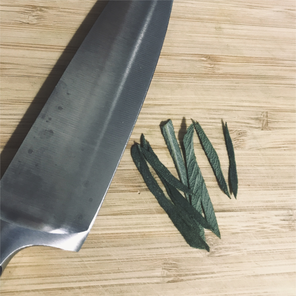 a knife beside a sage leaf cut into strips