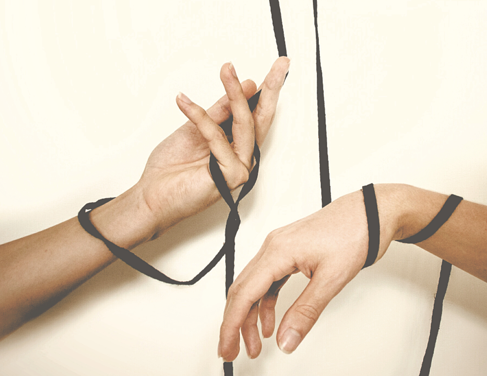 hands wrapped together in black ribbon