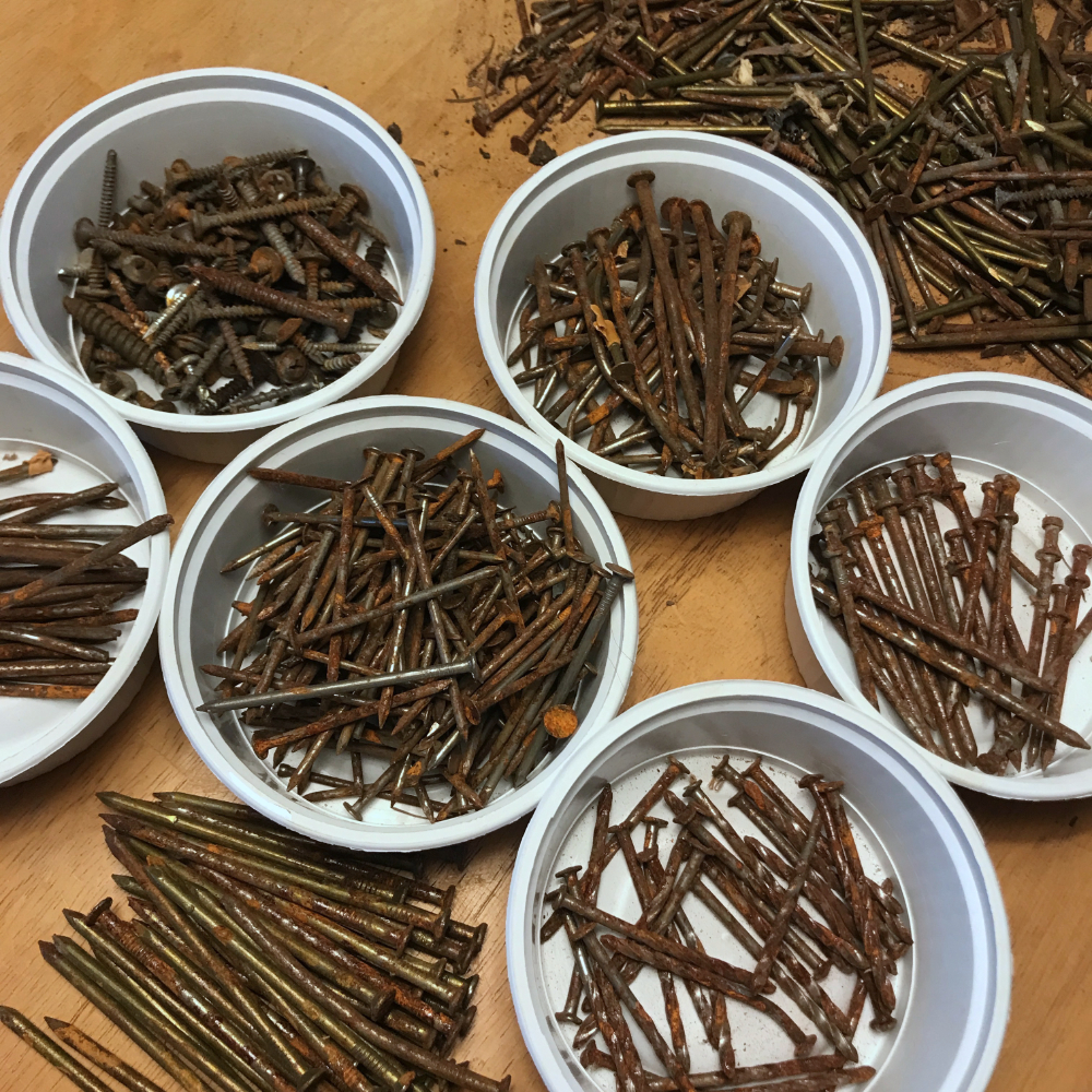 a variety of rusty nails and screws sorted into small white containers