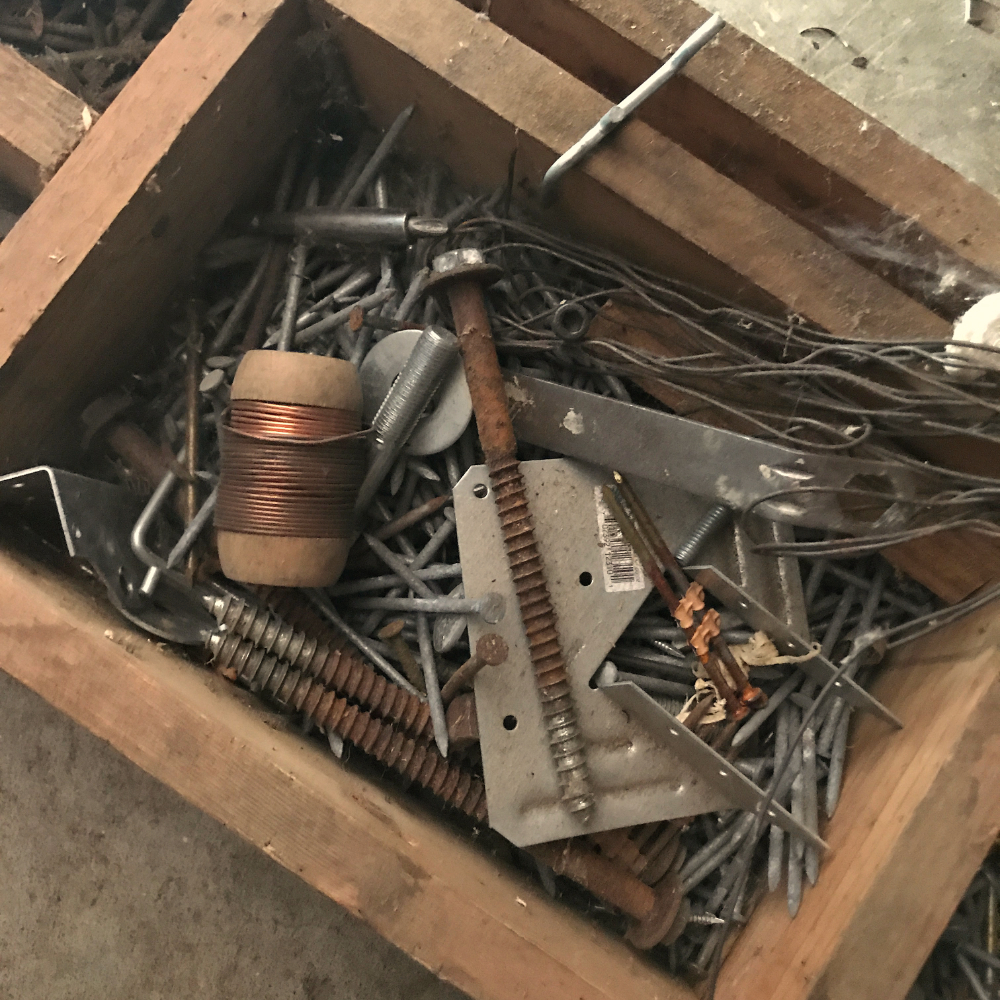 a wooden box filled with a jumble of hardware, half of it rusted.