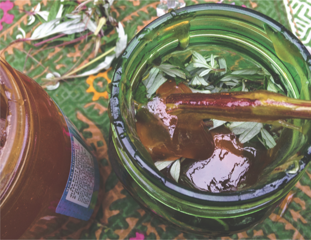 a jar of liquid with honey being stirred into it