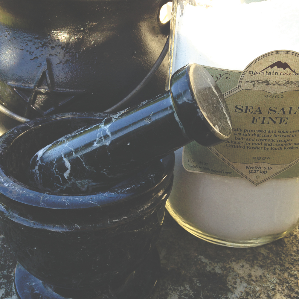 a small cauldron, a mortar and pestle, and a large jar of sea salt