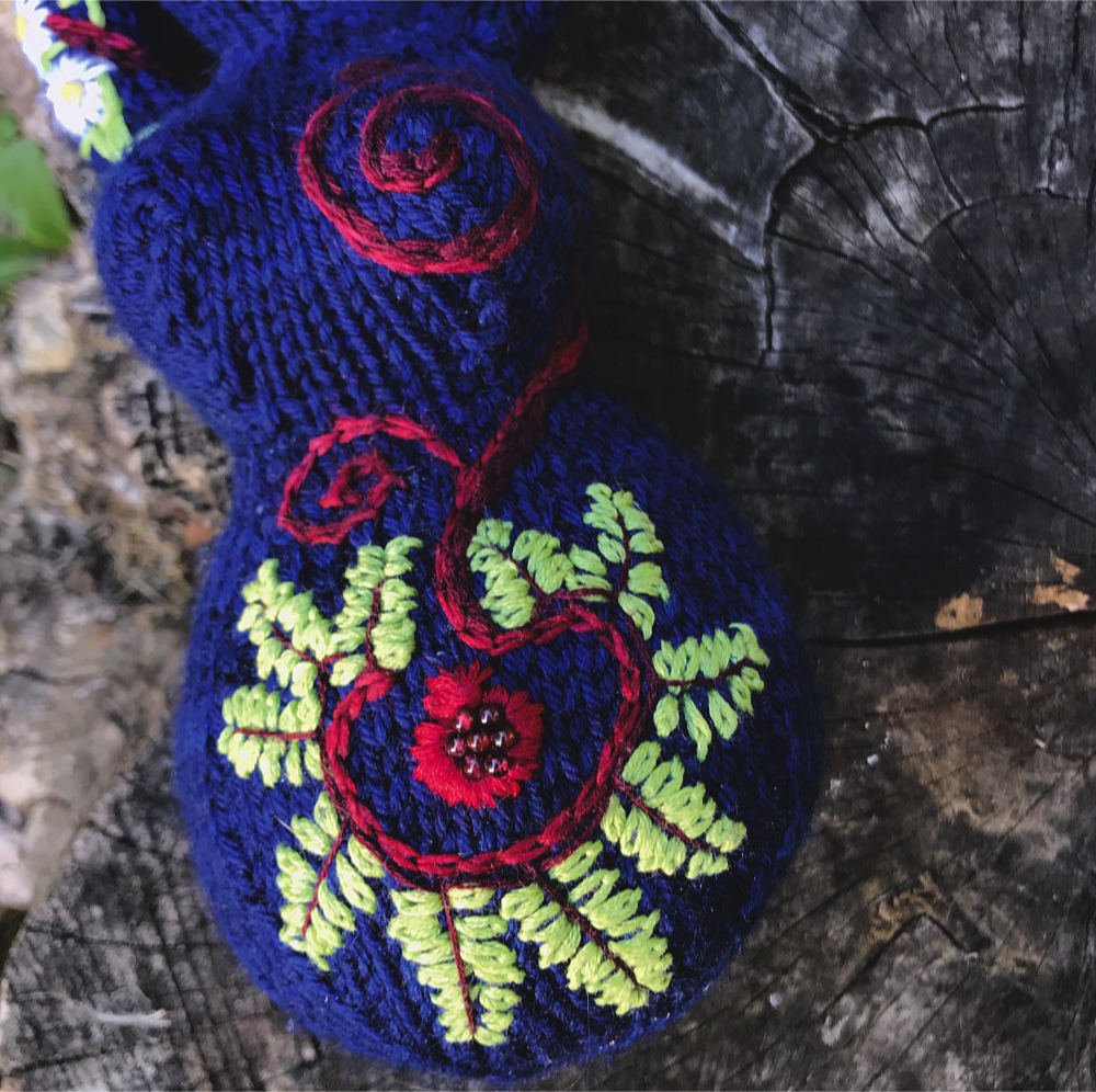 closeup of ferns and pomegranate embroidered on a knitted goddess