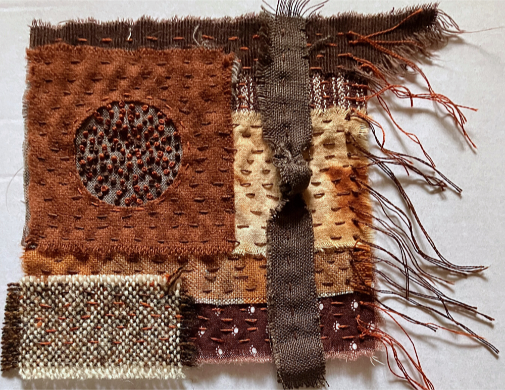 a fabric collage in shades of rust and brown, with lines of running stitch over the surface.