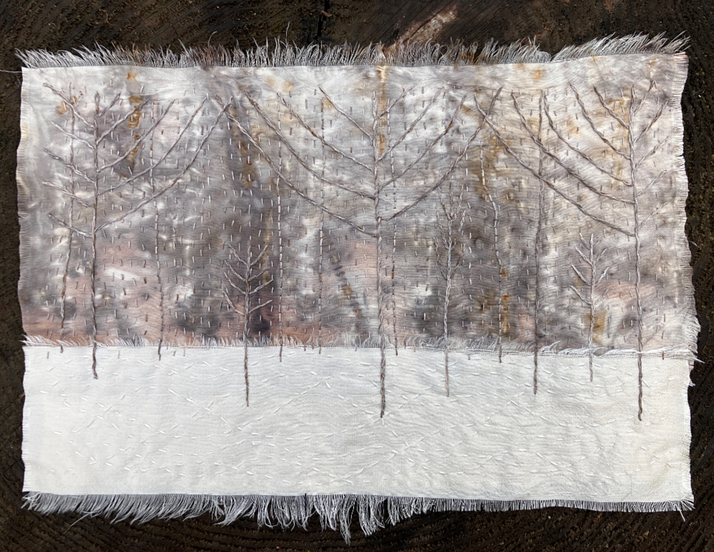 A rectangular art piece featuring white silk, and silvery gray, white, and tan mottled silk, stitched with stylized, bare branched winter trees.