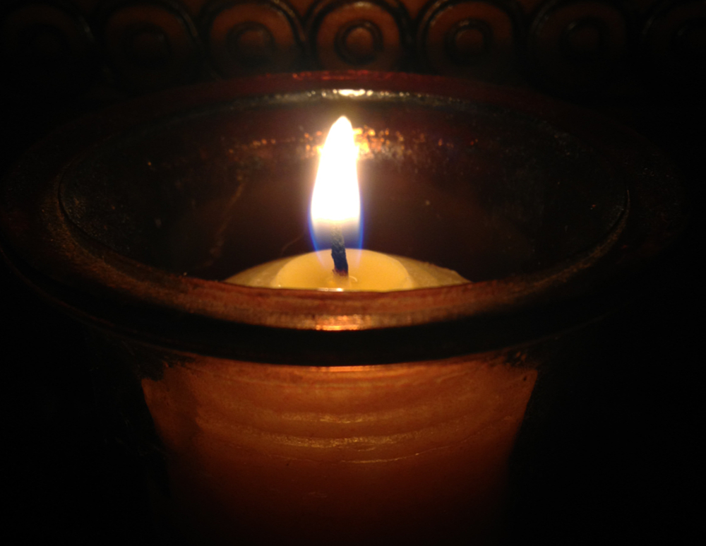 A votive candle burning in the darkness